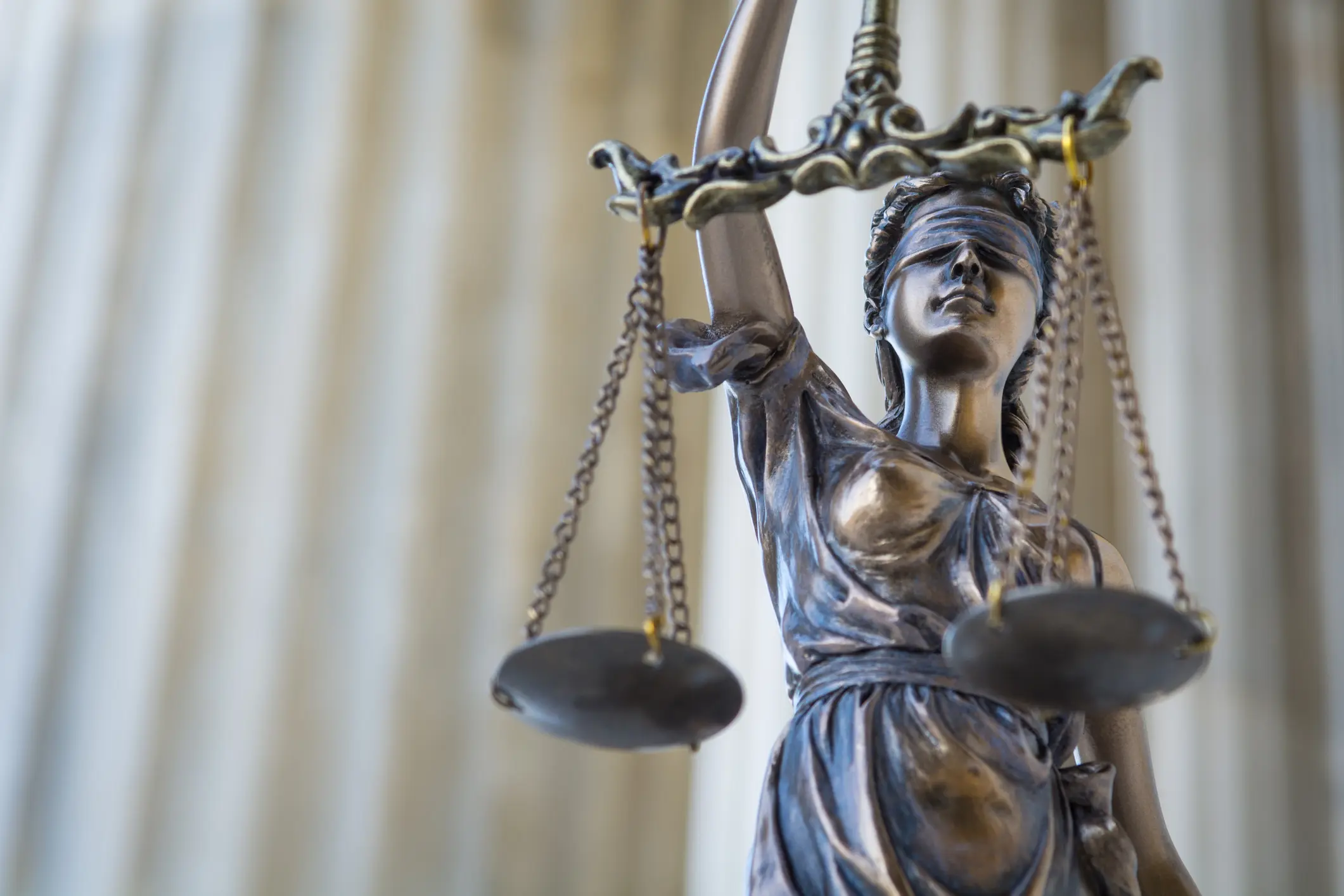 The statue of justice Themis or Justitia, the blindfolded goddess of justice against ionic order colonnade, with copy space
