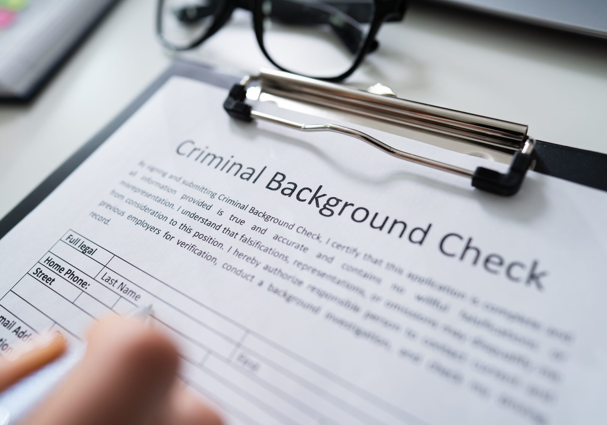 Close-up Of Human Hand Filling Criminal Background Check Application Form With Pen