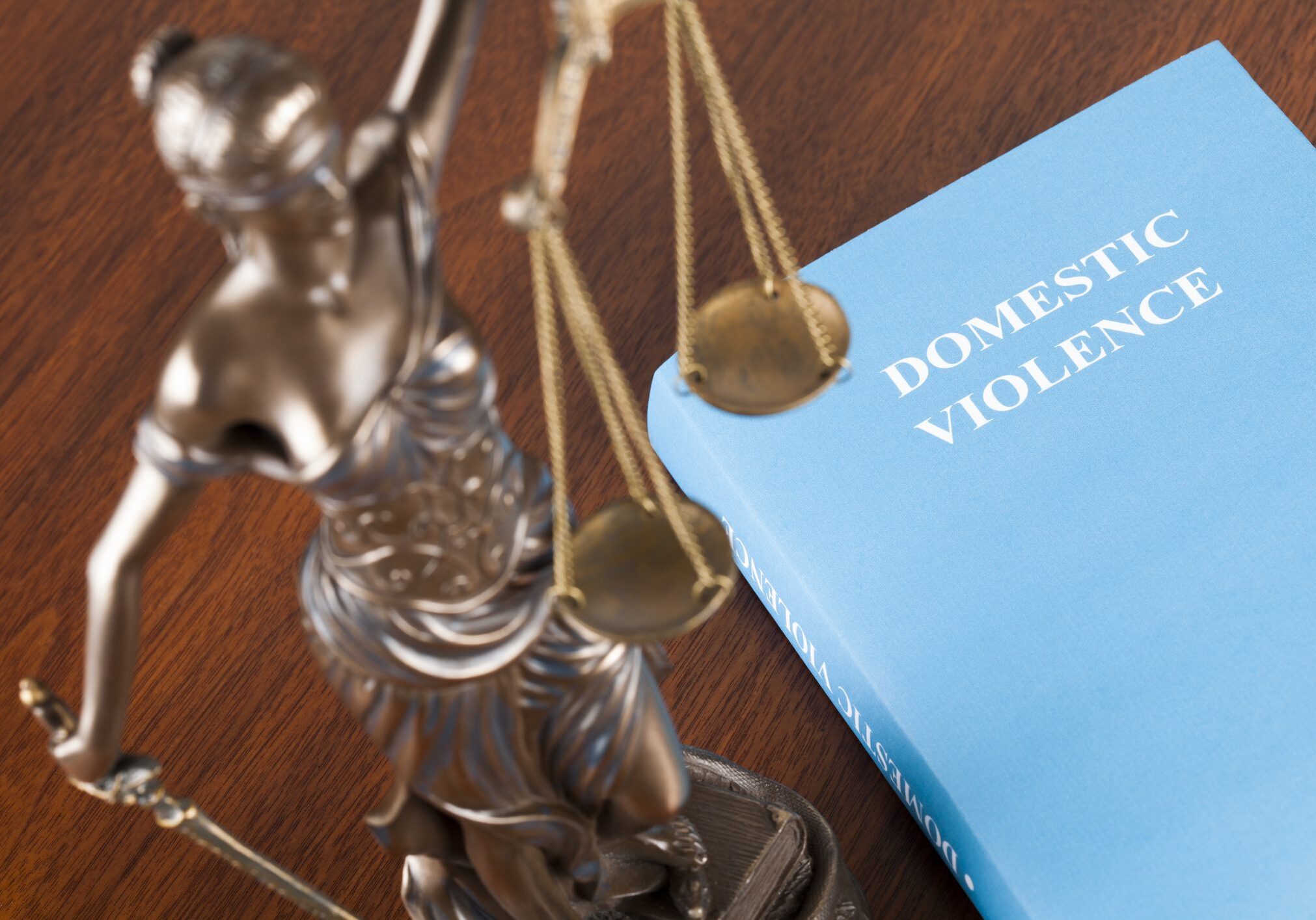 A mock law book on domestic violence next to Lady Justice. Selective focus.