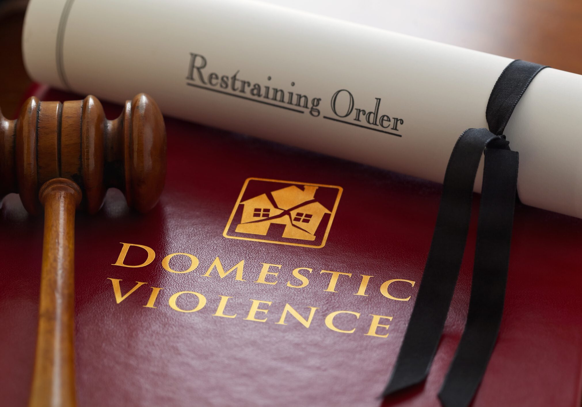 The Law with respect to family related, domestic violence issues. Book of law with a gavel and a Restraining Order.